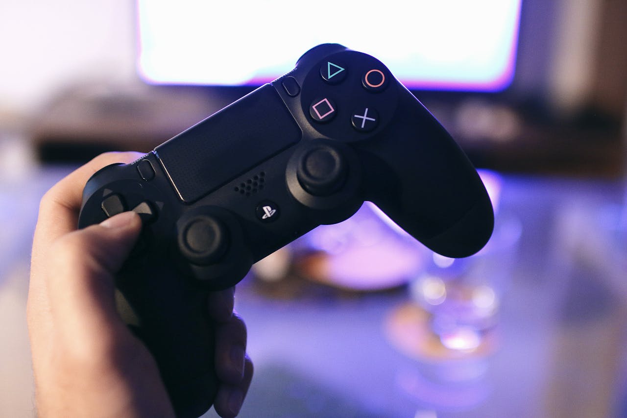about-02 Person holding a gaming controller, blurred screen in background.