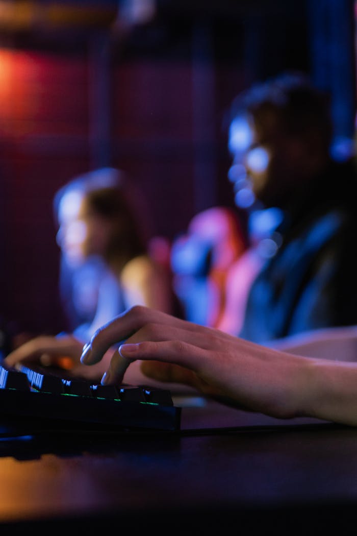 services-05 Close-up of hands typing on a keyboard during an intense gaming session in a dimly lit room.