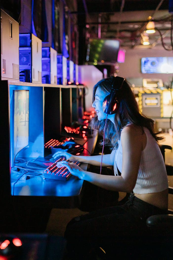 about-03 A woman intensely focused on a gaming computer in an esports setting with vibrant lighting.